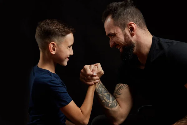 Vader en zoon tijdens vriendschappelijke arm worstelwedstrijd op zwart — Stockfoto