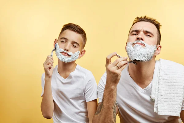 Padre e hijo afeitándose sobre fondo amarillo — Foto de Stock