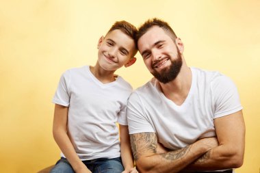 Baba ve küçük oğlu stüdyo arka planında izole edilmiş kameraya gülümsüyor.