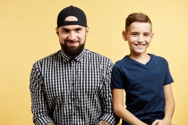 Baba ve küçük oğlu stüdyo arka planında izole edilmiş kameraya gülümsüyor.