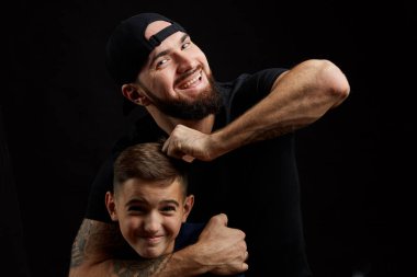 Oğlu ve babası siyah arka planda eğleniyor.