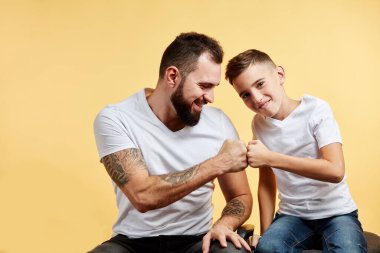 Baba ve oğul hoş bir gülümsemeyle birbirlerine yumruk tokuştururlar.