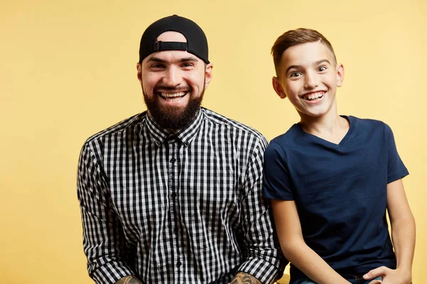 Pai e filho pequeno sorrindo para câmera isolada no fundo do estúdio — Fotografia de Stock