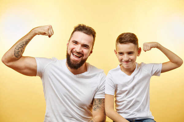 bearded father and his son looking at camera and smiling while show biceps