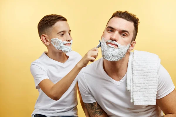 Pai e filho de barbear no fundo amarelo — Fotografia de Stock