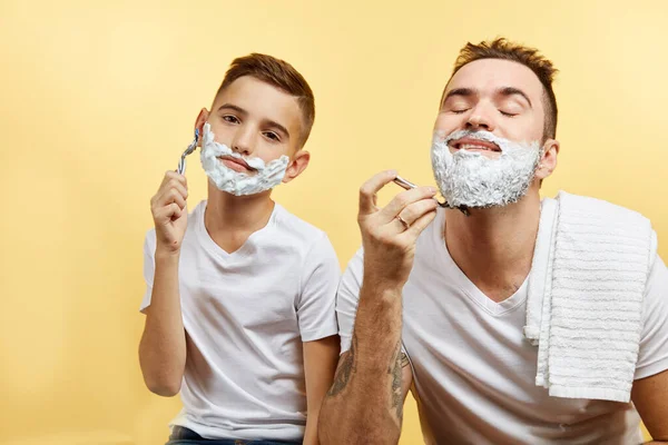 Padre e hijo afeitándose sobre fondo amarillo — Foto de Stock