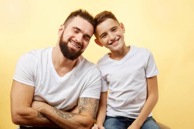 Baba ve küçük oğlu stüdyo arka planında izole edilmiş kameraya gülümsüyor.