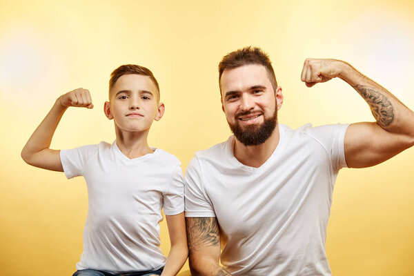bearded father and his son looking at camera and smiling while show biceps