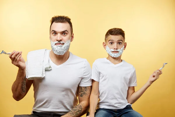 Pai e filho de barbear no fundo amarelo — Fotografia de Stock