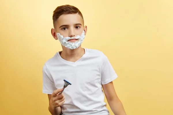 Shoking boy se preparando para barbear rosto sobre fundo amarelo — Fotografia de Stock