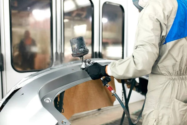 Lavoratori che dipingono parti di auto in garage speciale, indossando costume e indumenti protettivi — Foto Stock