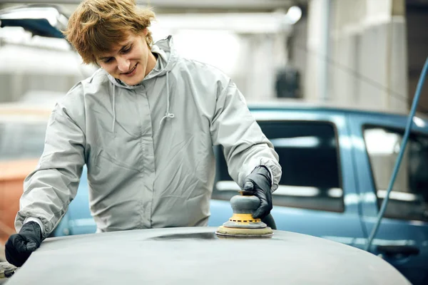 Mecánico muele la pieza del coche para pintar. Trabajo de carrocería pintura de reparación de automóviles después del accidente — Foto de Stock