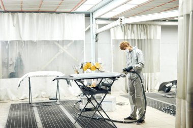 Tamirci boya için araba parçalarını öğütüyor. Araba kaportası kazadan sonra boyayı tamir eder.