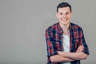 Mutlu genç adam. Kollarını kavuşturup gülümseyen yakışıklı bir gencin portresi.