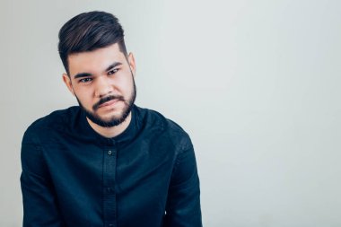 Kolları bağlı yakışıklı bir adam kameraya bakıyor.