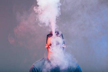 Vaper duvarın yanında elektronik sigara içiyor.
