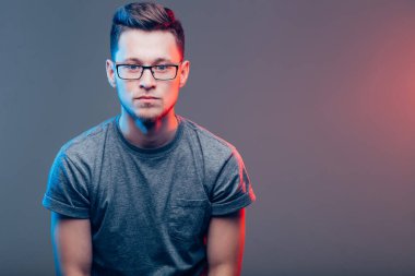 Kolları bağlı yakışıklı bir adam kameraya bakıyor.