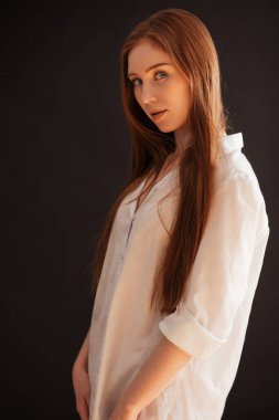 Güzel kızıl saçlı kız kameraya siyah b 'ye bakıyor.