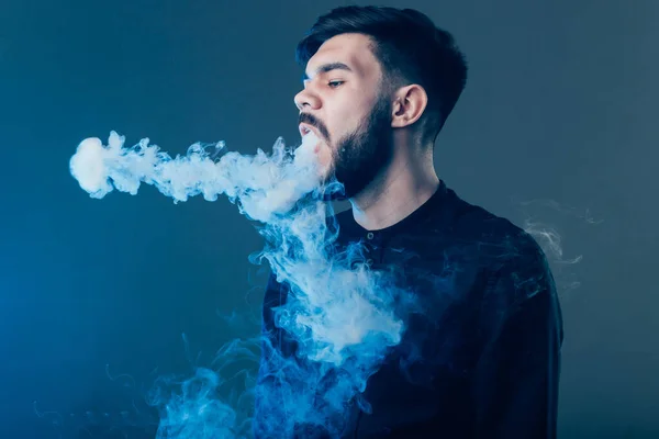 Ένας άντρας με γενειάδα να καπνίζει ηλεκτρονικό τσιγάρο. Εξατμιστήρας καπνού hipster. — Φωτογραφία Αρχείου