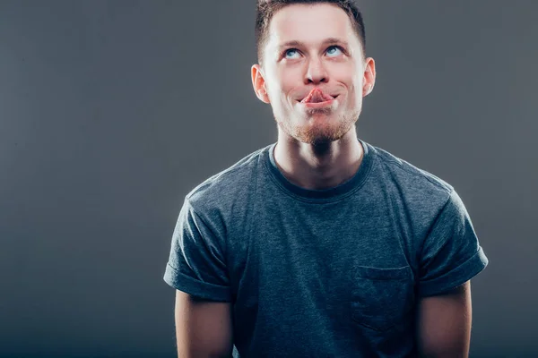 Muž ukazuje svůj jazyk přes šedé pozadí — Stock fotografie