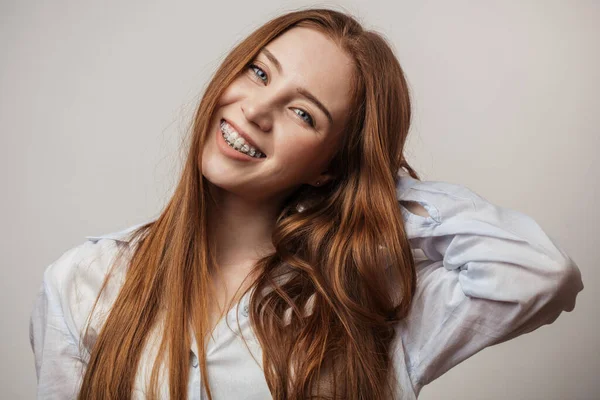 Šťastná mladá rusovlasá žena v rovnátkách s úsměvem na bílém pozadí — Stock fotografie