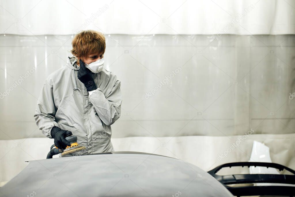 mechanic grinds car part for painting. Car body work auto repair paint after accident