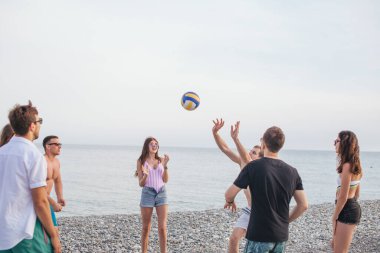 İnsanlar yaz günü eğlenir ve plaj voleybolu oynarlar.