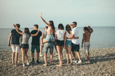 Mutlu erkekler ve kadınlar plajda yürüyüş yapar arkadaşlarıyla plaj tatilinin tadını çıkarırlar.