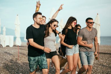 Tatil, tatil. Bir grup arkadaş sahilde eğleniyor, yürüyor, bira içiyor, gülümsüyor ve sarılıyorlar.