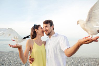 Parktaki çift yerel güvercinlerle oynuyor, turistler eğleniyor.