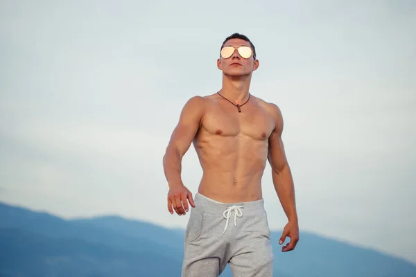 Homem de corpo masculino em óculos de sol na praia com mountauns no fundo — Fotografia de Stock