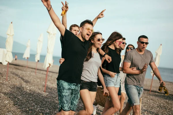 Ünnepek, nyaralás. baráti társaság szórakozás a strandon, séta, sörözés, mosolygás és ölelés — Stock Fotó