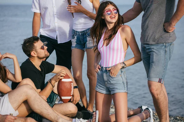 Mensen die samen leuke tijd doorbrengen terwijl ze op het strand zitten, plezier hebben en bier drinken — Stockfoto