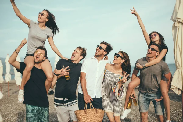 Gruppo di amici che camminano in spiaggia, divertirsi, cavalcare le donne su uomini, vacanza divertente — Foto Stock