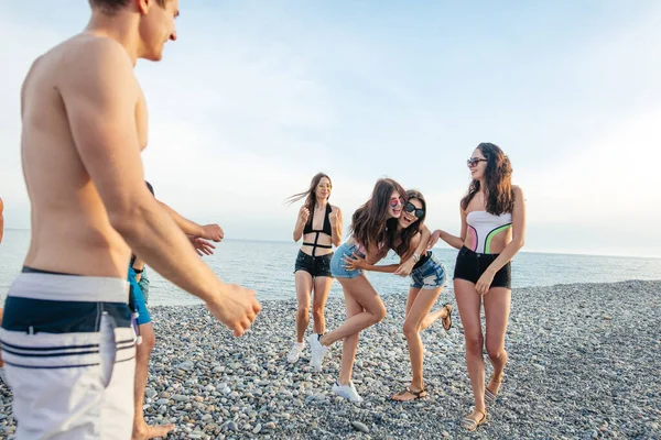 Amigos bailan en la playa bajo la luz del sol puesta del sol, divertirse, feliz, disfrutar — Foto de Stock