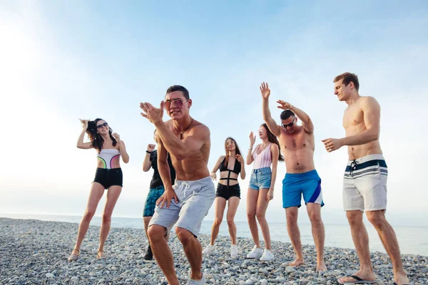 Amigos bailan en la playa bajo la luz del sol puesta del sol, divertirse, feliz, disfrutar — Foto de Stock