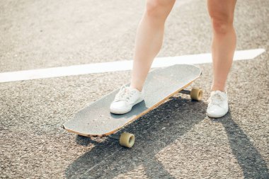 Longboard ve insanların kavramı - kadın bacakları yol boyunca sörf tahtasında