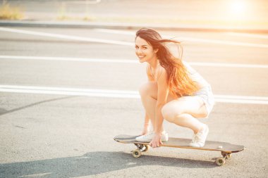 Güzel genç kız güneşli havada oturur ve sörf tahtasına biner.