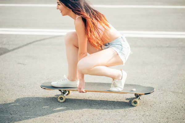 Mooi jong meisje zit en rijden op longboard bij zonnig weer — Stockfoto