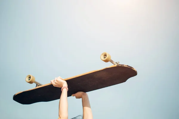 Portret van een mooie jonge volwassen vrouw met skateboard op de schouder — Stockfoto