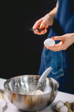 Şekerci, bir yumurtayı çelik kaba kırıyor.