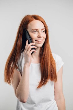 Gülümseyen, uzun saçlı, cep telefonuyla konuşan çekici bir kız.