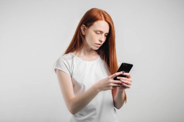 Temiz çilli kızıl saçlı kız akıllı telefon kullanıyor..