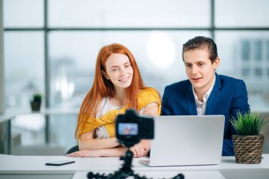 İki video blogcusu bir şey hakkında konuşuyor ve gülümsüyor.