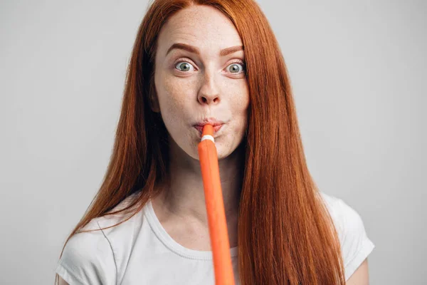 Funny lovely pinup girl blowing in party whistle and holding copyspace on palms — Stock Photo, Image