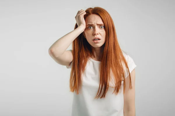 Redhead girl on white background with strong expression of fear, round eyes — Stock Photo, Image