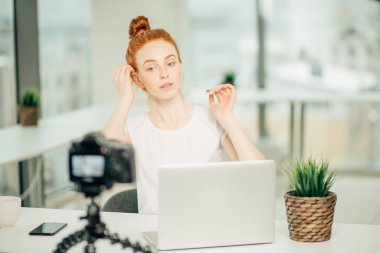 Genç bir kadın video blogu için saç dersi yayınlıyor.