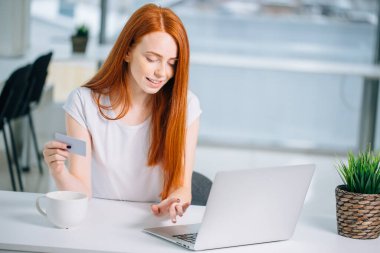 İnternetten bilgisayar ve kredi kartıyla alışveriş yapan kız.