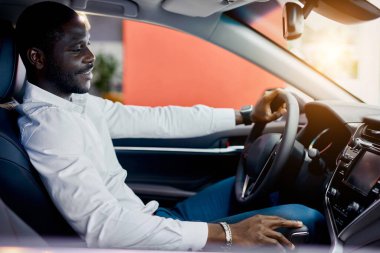 Zengin Afrikalı adam yeni bir otomobilin direksiyonunda kendini deniyor.