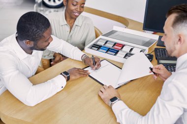 Siyahi müşteriler pazarlamacıyla masaya otururken sözleşme imzalarlar.